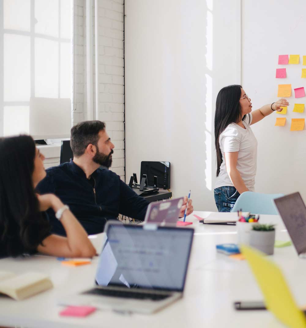 Three co-workers brainstorming with post-it notes.